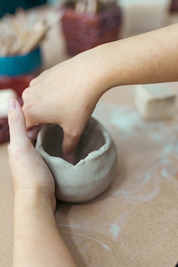 A person is making a vase out of clay