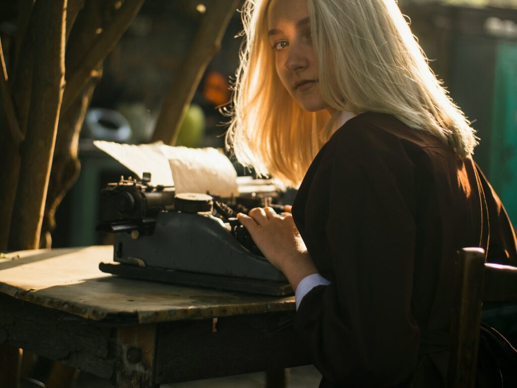 a woman sitting at a table typing on an old fashioned typewriter